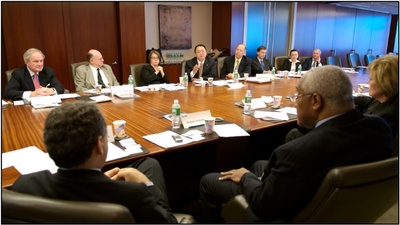 photo of business professionals sitting & talking around conference room table